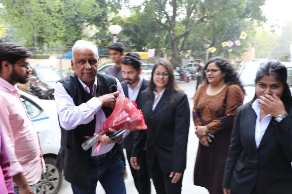 Professor Jagdeep Singh Chhokar holding flowers while arriving at an event with students